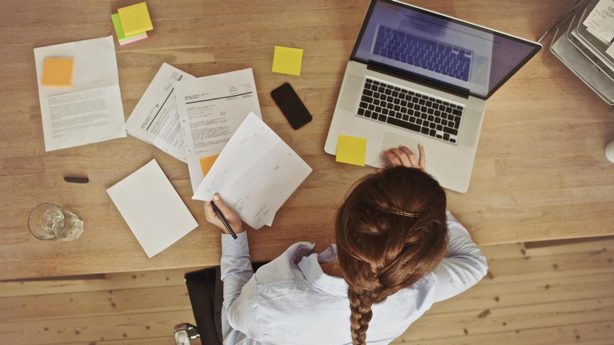 OTO BAJADA DE 123RF EL 17 DE MAYO DEL 2019. PARA ILUSTRAR EL ARTICULO &#039;Trabaja más rápido con estos consejos&#039;. High angle view of an young brunette working at her office desk with documents and laptop. Businesswoman working on paperwork. PLANO CENITAL DE UNA MUJER TRABAJANDO CON UN ORDENADOR PORTATIL. OFICINA, TRABAJO, ORDENADOR, PORTATIL, EJECUTIVA, NEGOCIO. FOTO DE 123RF