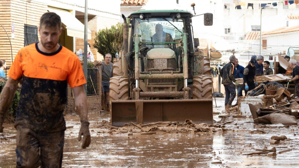 Varias personas colaboran en la limpeza de una calle afectada en la localidad de Utiel, este viernes.