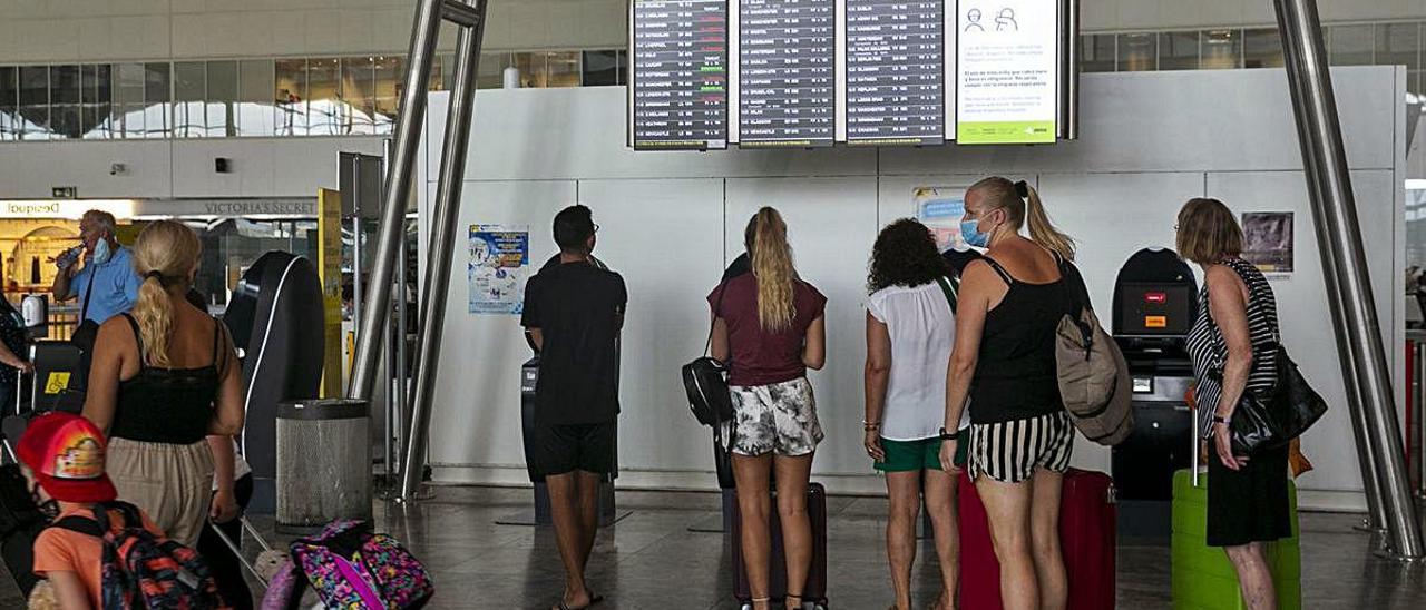 Pasajeros consultando ayer los horarios de sus vuelos en la terminal de salidas del aeropuerto de Alicante-Elche.