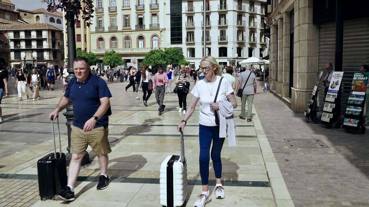 Turistas con sus maletas en la plaza de la Constitución de Málaga.