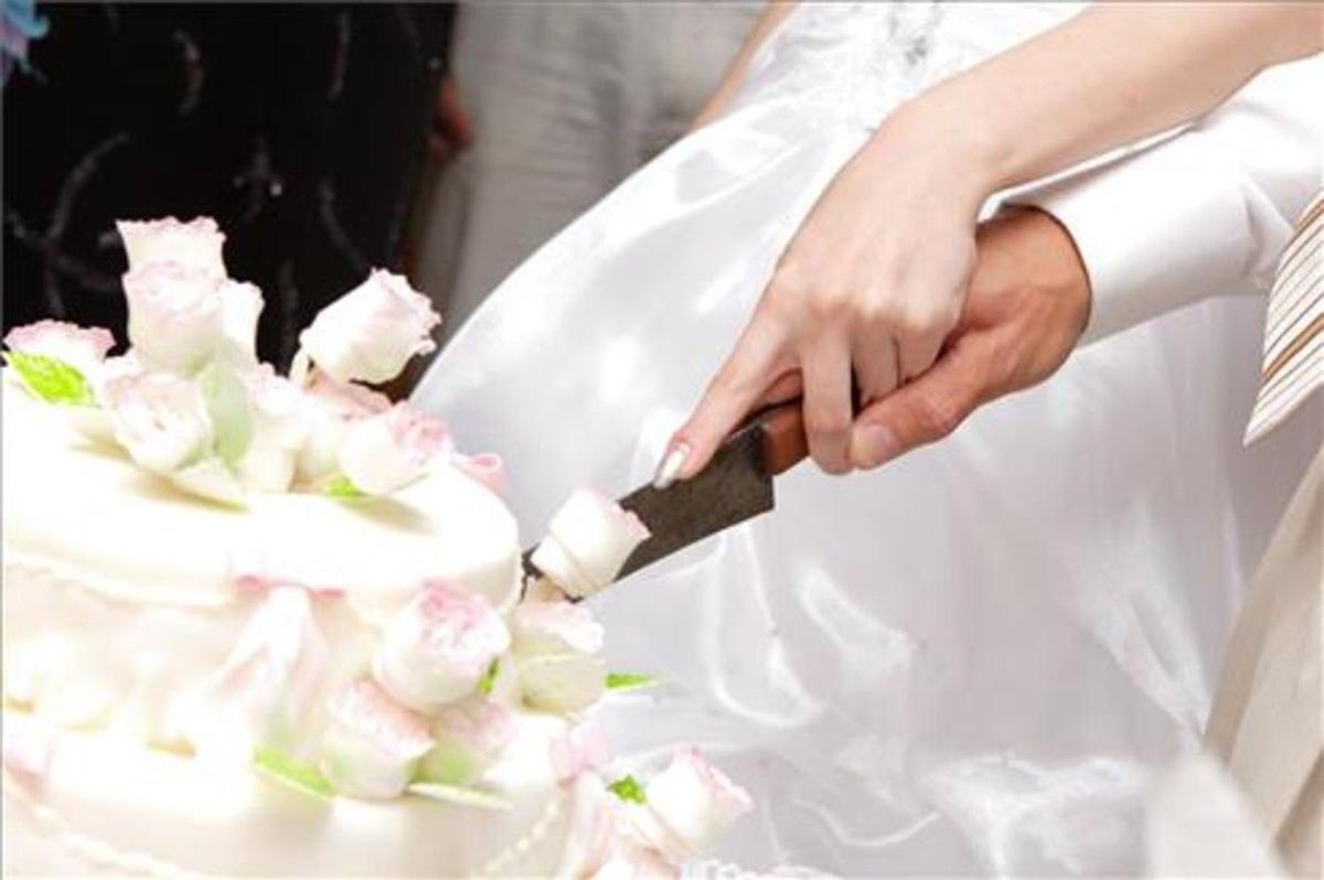 Unos novios cortan un pastel de boda.