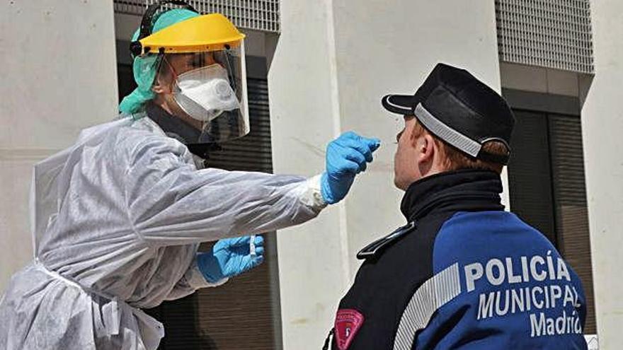 Una sanitària realitzant la prova del coronavirus a un policia.