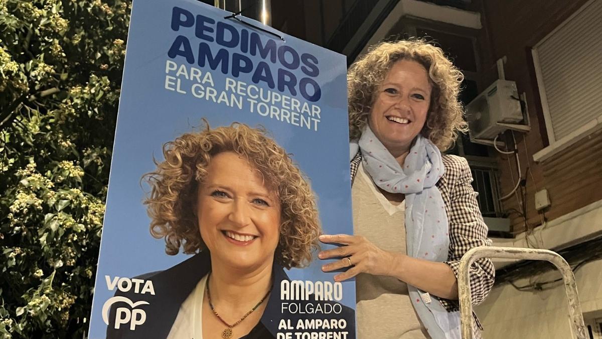Amparo Folgado cuelga uno de los carteles con su imagen de la presente campaña electoral.
