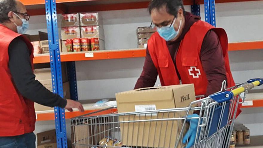 Fidel (izquierda) y José Antonio (dercha) a la espera de una usuaria del programa de alimentos. | E. P.