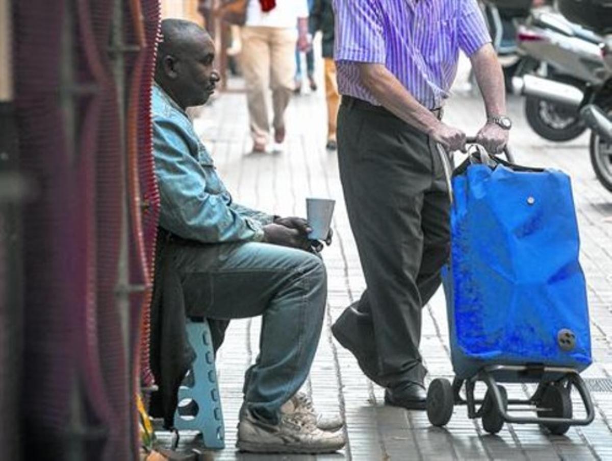 Un hombre pide limosna a la puerta de un supermercado de Barcelona.