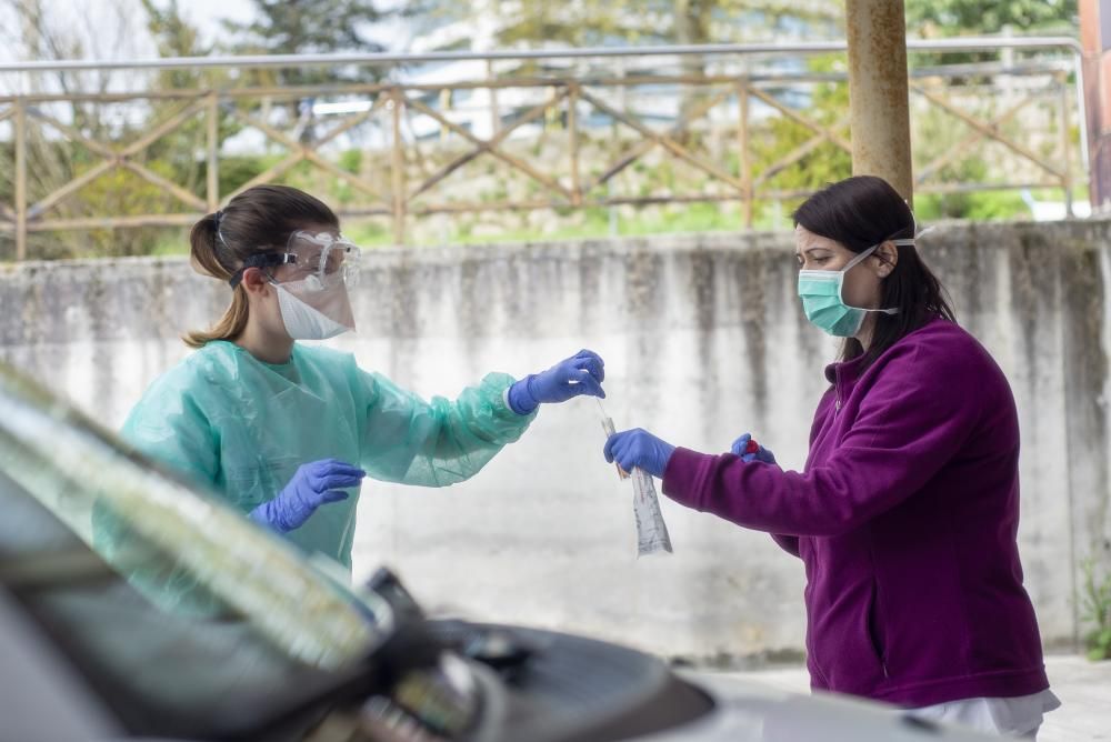 Una enfermera del CHUO realiza una prueba a una mujer en la zona habilitada para el test del coronavirus. // Carlos Peteiro