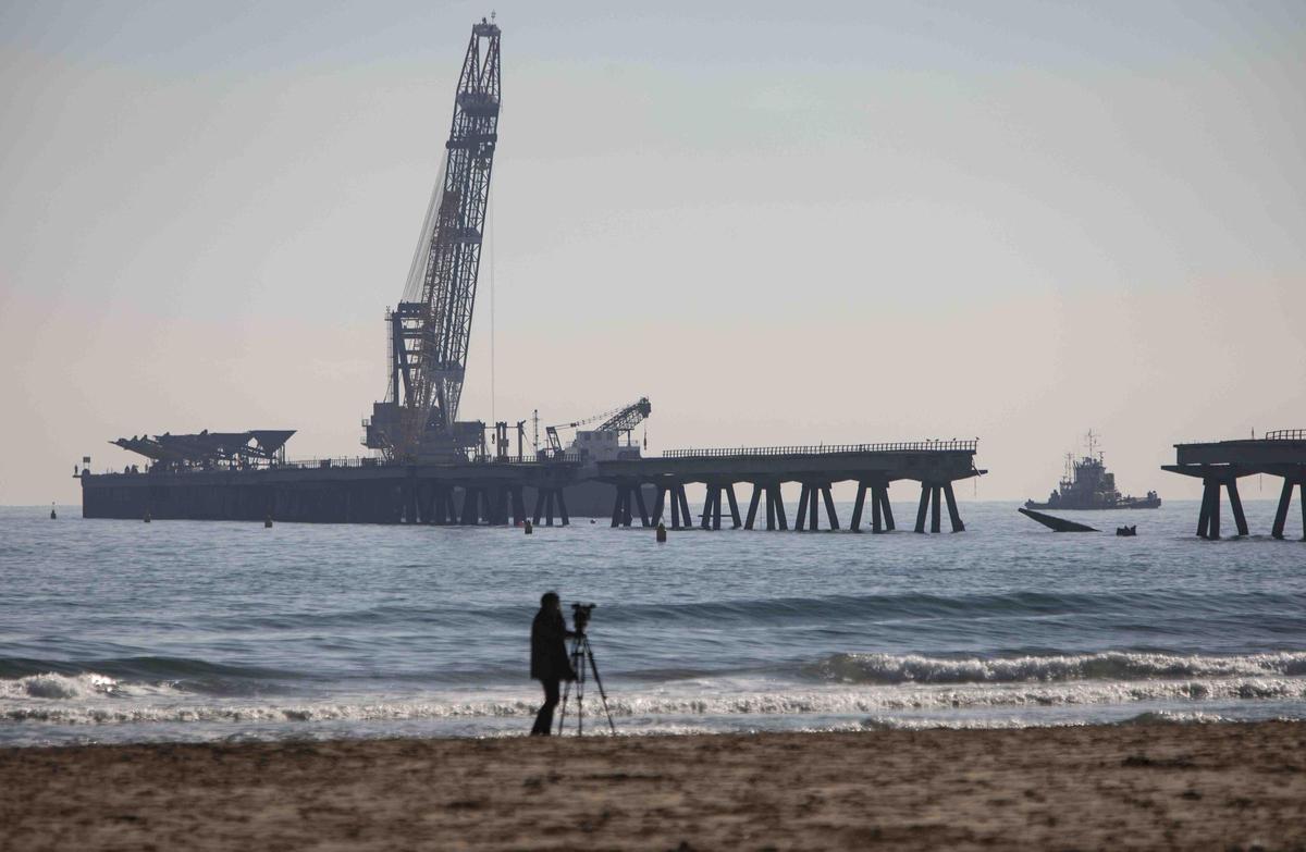 Vecinos del Port de Sagunt observan desde la playa la retirada de las tolvas del Pantalán