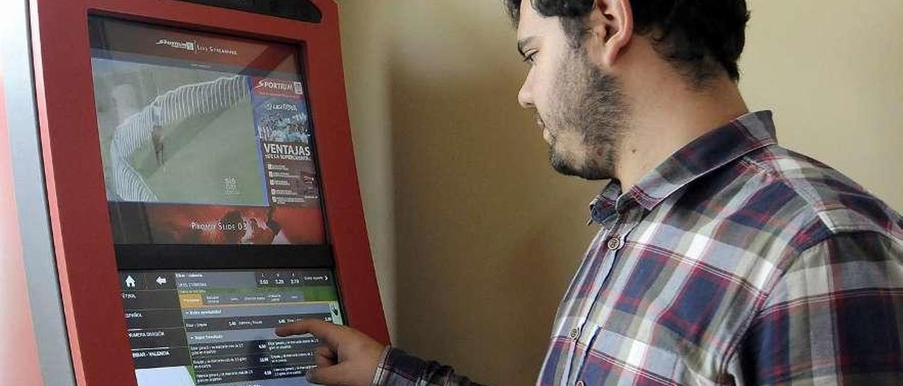 Un joven manipula una máquina de apuestas deportivas en un bar de Lalín. // Bernabé/Javier Lalín