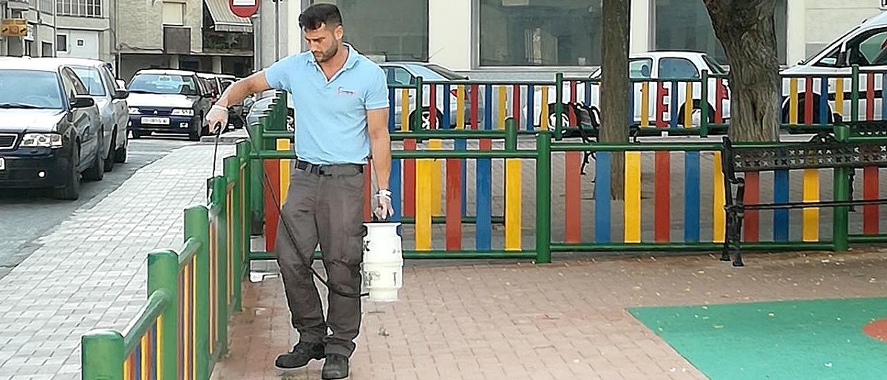 Un operario fumiga la valla de un parque infantil situado entre las calles Vendimia y Jubilados y Pensionistas.