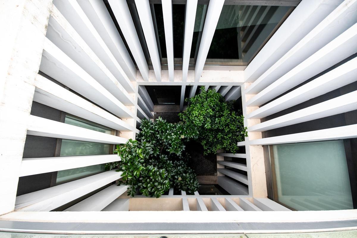 El patio central, delimitado por pilares de hormigón blanco, conecta visualmente las distintas plantas del edificio.