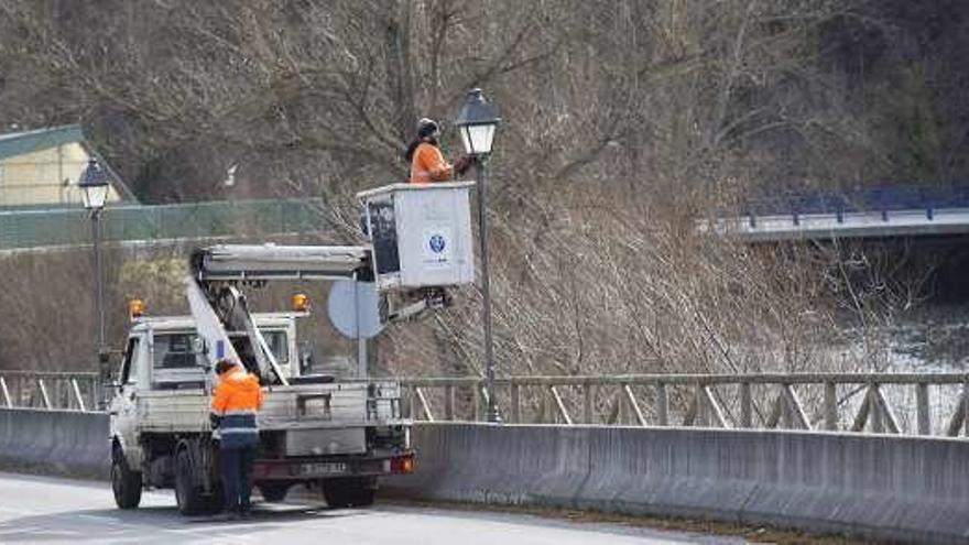 Operarios limpiando farolas en Sobrescobio.