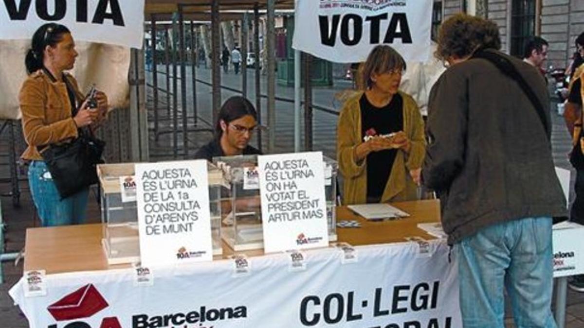 URNAS SIMBÓLICAS Un punto de votación de la Rambla da a elegir a los electores entre depositar el sobre en la urna de Arenys de Munt o en la que utilizó en secreto el 'president', Artur Mas, en la sede de Òmnium.