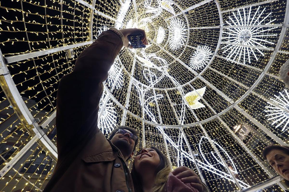 Transeúntes ante las luces de Navidad en Málaga.