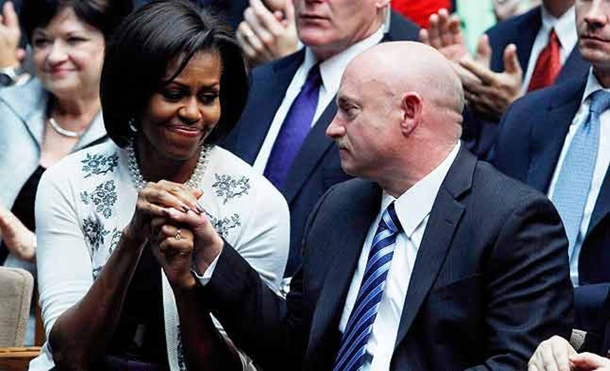 La primera dama nord-americana, Michelle Obama, agafa la mà del marit de la congressista ferida Gabrielle Gifford, mentre escolten el discurs del president Barack Obama en suport a les víctimes del tiroteig massiu a Tucson, Arizona.