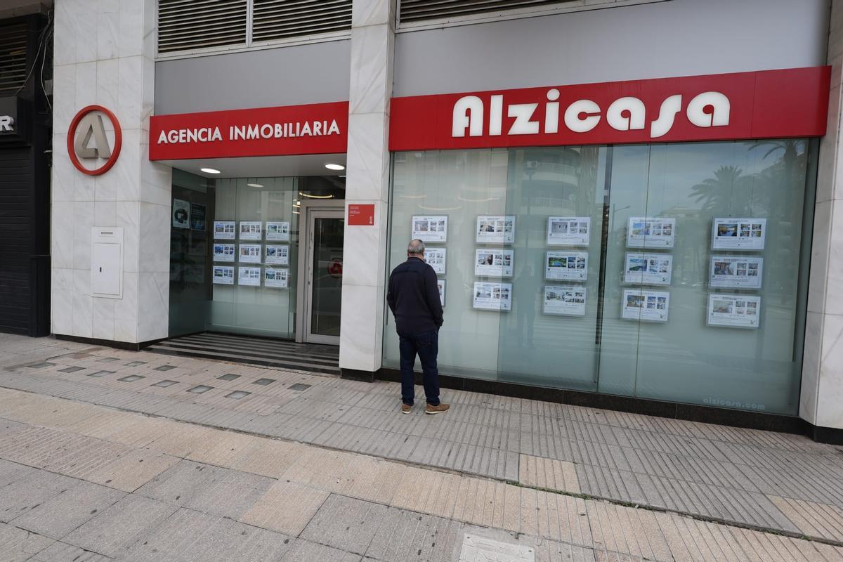 Un vecino observa  el esparate de una inmobiliaria de Alzira en una imagen de archivo.