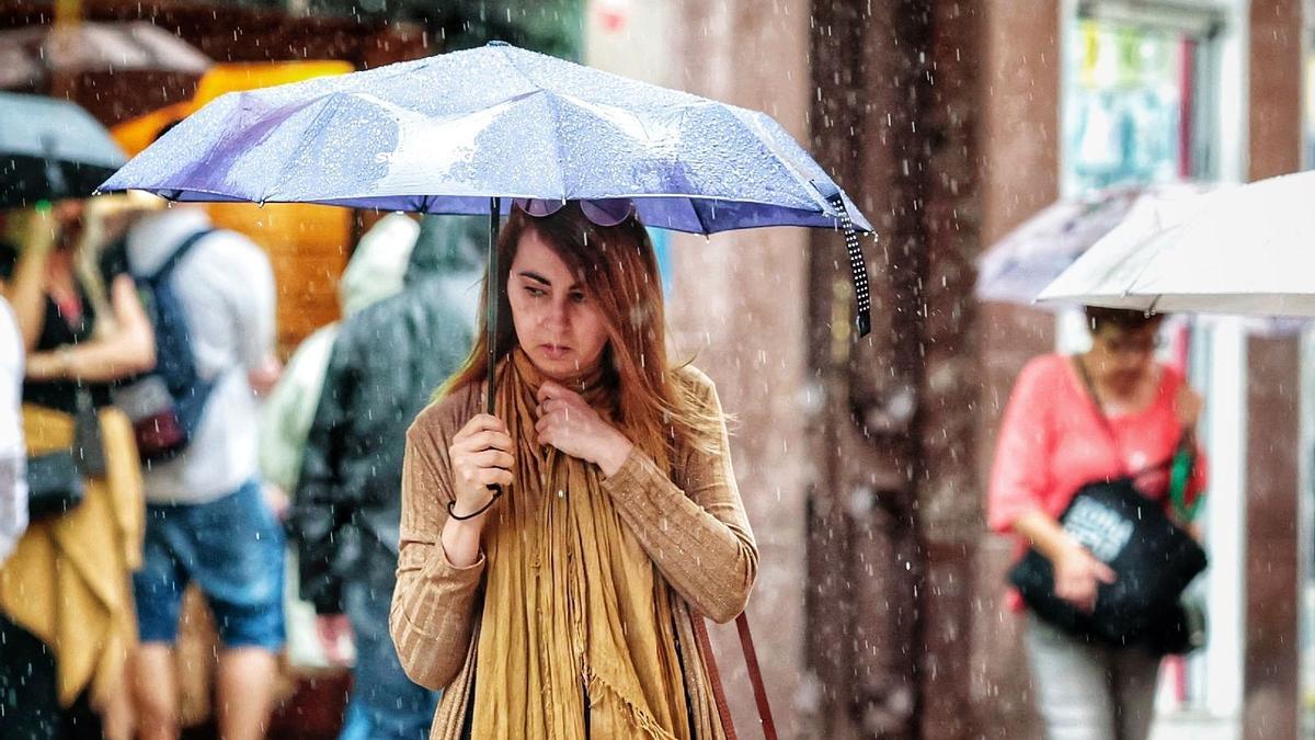 Una mujer se protege de la lluvia con un paraguas.