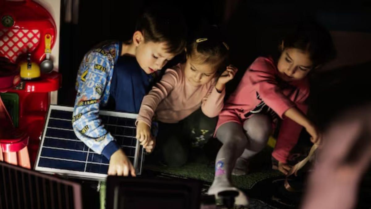 Niños jugando en casa durante un apagón usando iluminación alternativa con panel solar