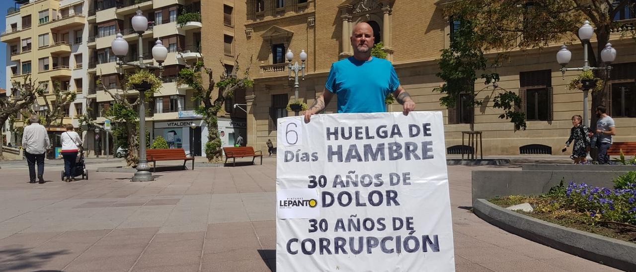 Guillermo posa con una pancarta en la plaza de Navarra de Huesca para dar a conocer su situación.