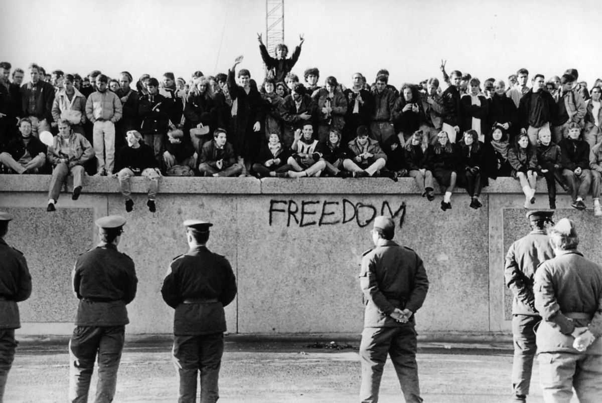 Estudiantes de Alemania oriental sentados sobre el muro de Berlín en Noviembre de 1989.