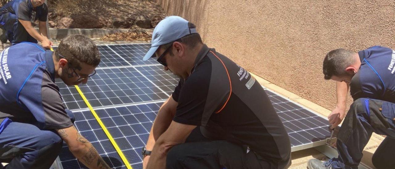 Varios jóvenes del curso de Femete trabajan en la instalación de un panel solar.