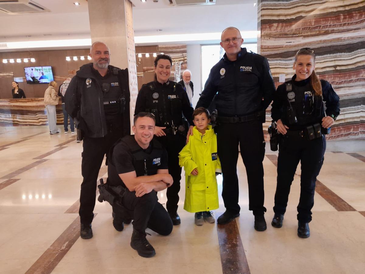 Policías locales de Alcúdia con el niño suizo de siete años en la puerta del hotel de sus padres