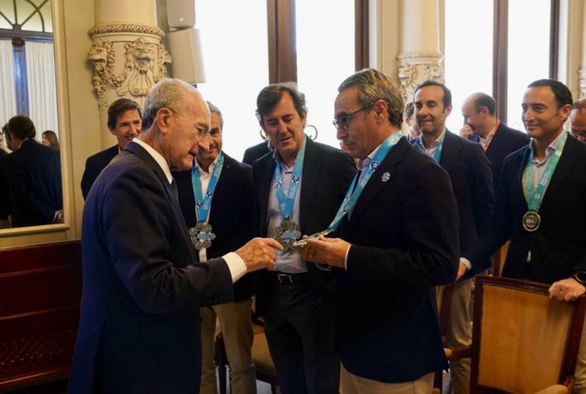 El grupo malagueño de ‘Los obradores’, con su medalla formada por las seis medallas de las grandes maratones, ayer delante del Ayuntamiento de Málaga