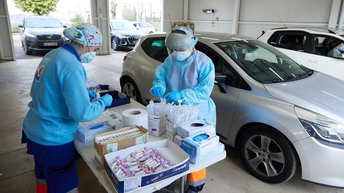 Dos enfermeras preparan el test en una mesa durante la realización de PCR en un autocovid en Sevilla