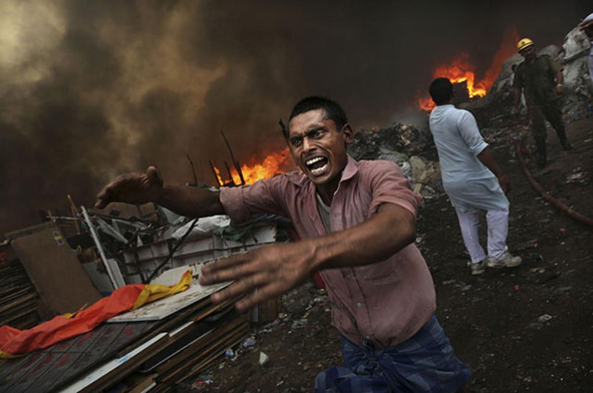 Un home demana cridant aigua per sufocar l’incendi que va arrasar un barri pobre de Nova Delhi.
