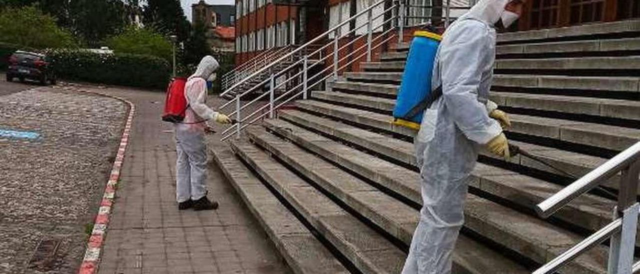 Dos trabajadores desinfectando ayer las escaleras de acceso al colegio Montedeva Alter Vía de Gijón.
