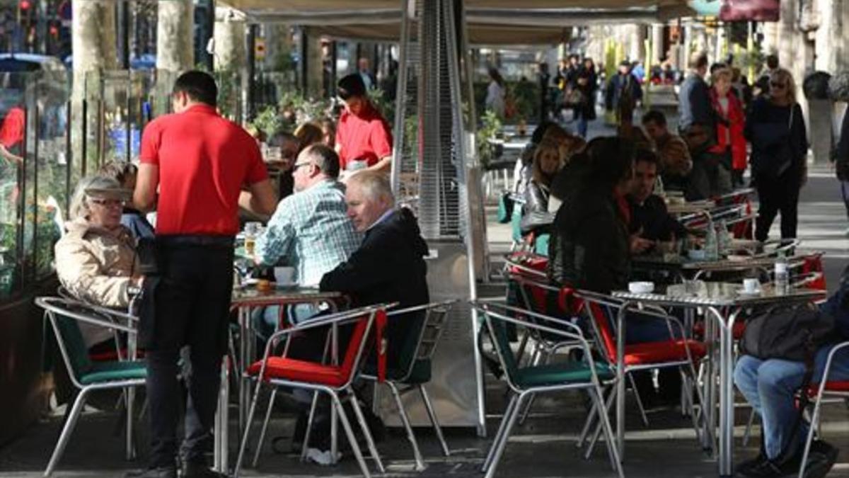 Varios camareros sirven a clientes en terrazas de bares del paseo de Gràcia.