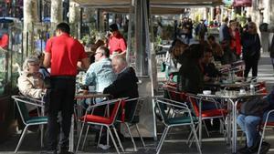 Varios camareros sirven a clientes en terrazas de bares del paseo de Gràcia.