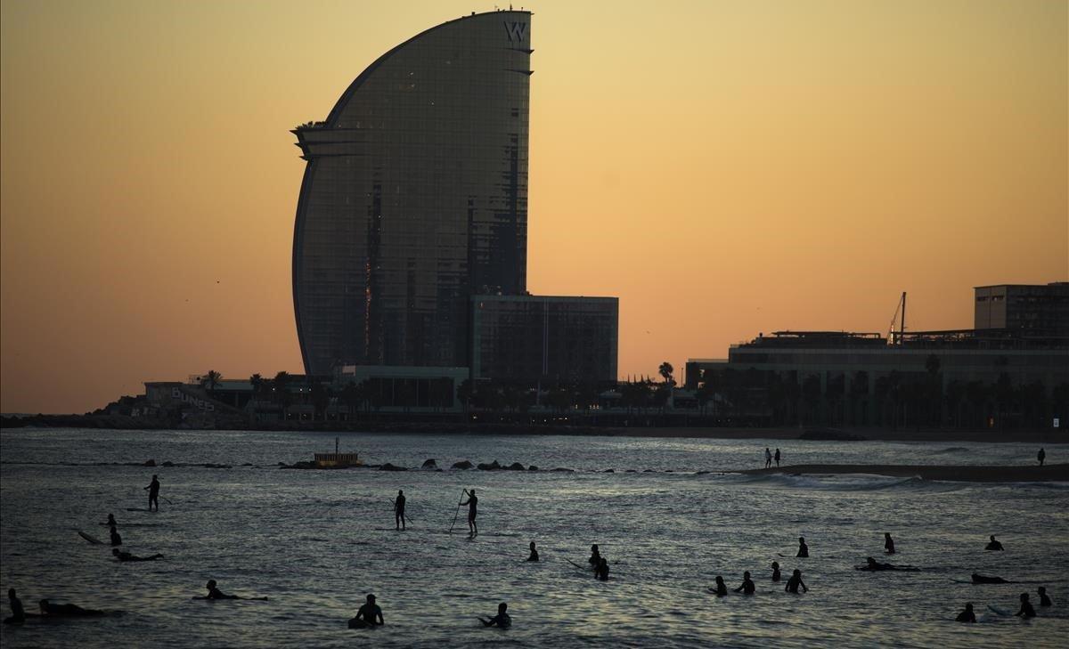 Gente surfea en la playa en Barcelona durante la fría tarde de invierno, tras la llegada de una ola de frío.