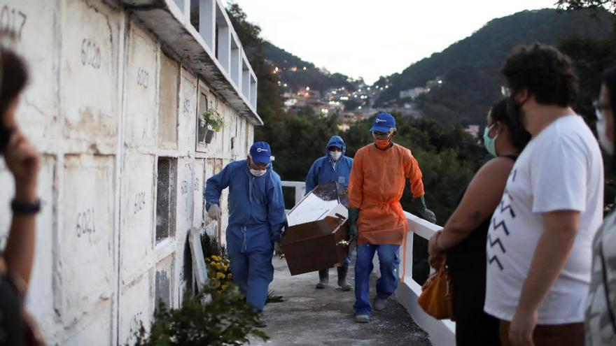 Varias personas observan cómo trasladan un ataúd en Río de Janeiro.