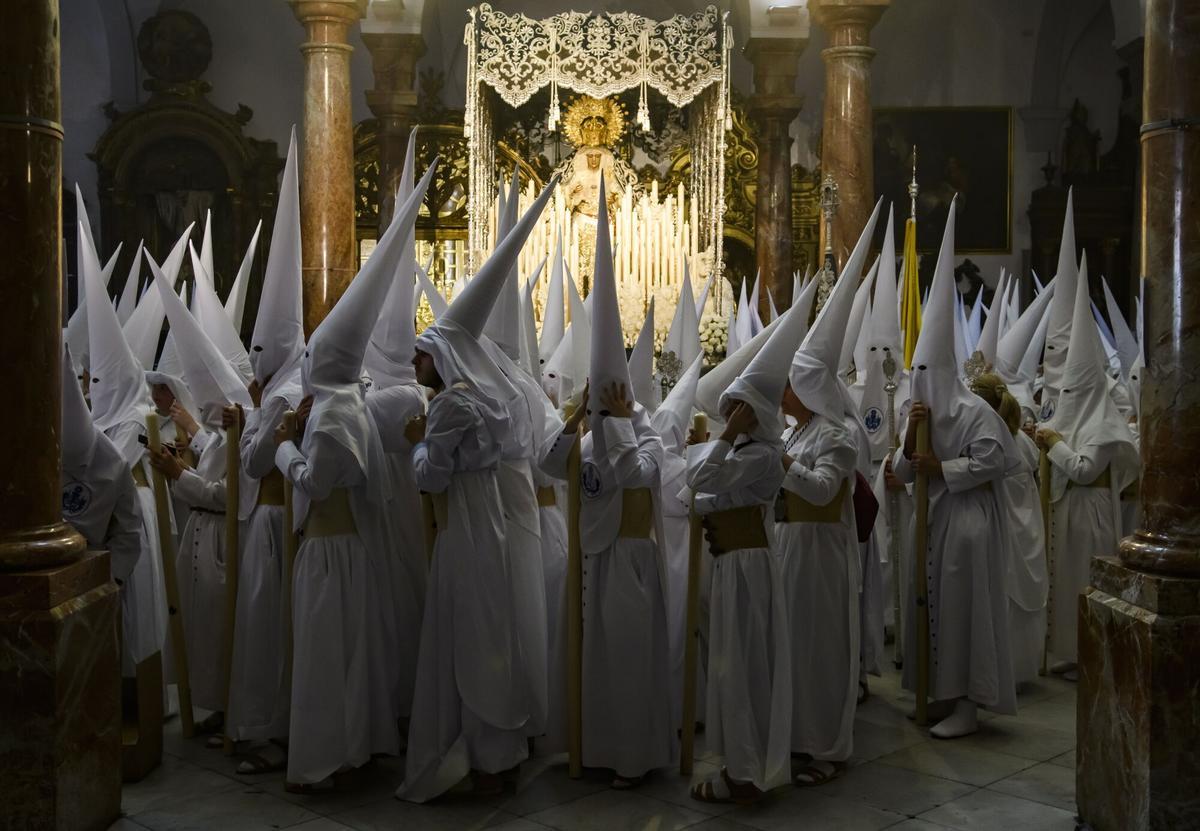 Nazarenos de la Hermandad de La Candelaria esperan ante el paso de palio de la Virgen de La Candelaria.