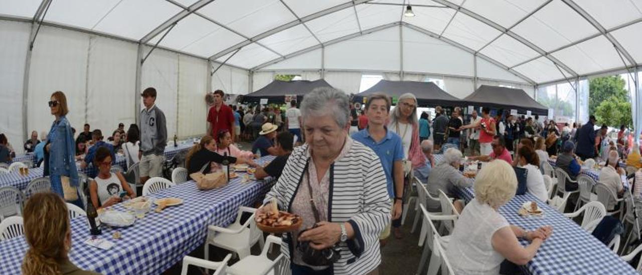 Una mujer se dirige a su sitio en la carpa con una ración de pulpo á feira.   | // GONZALO NÚÑEZ