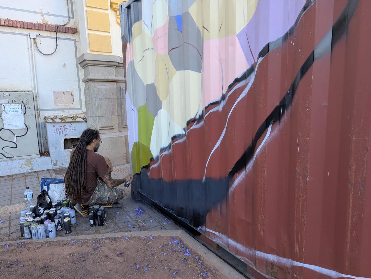 El artista, pintando el contenedor.