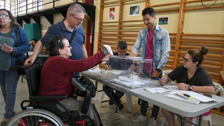 Una votante en silla de ruedas introduce el voto en la urna