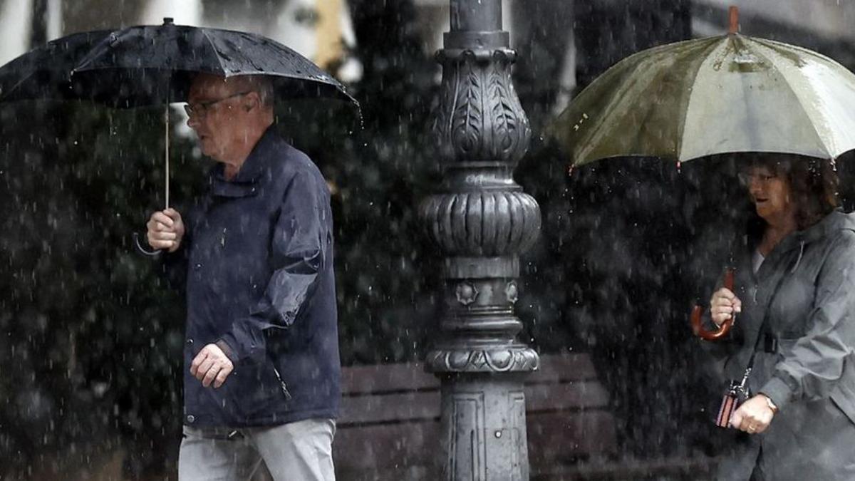 Dos personas caminan bajo la lluvia.