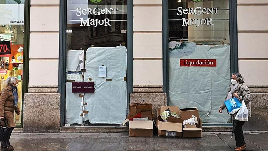 Dos mujeres pasan por delante de la tienda ya cerrada de Sergent Major en Zamora, en cuyo escaparate las trabajadoras han colgado un mensaje de agradecimiento. | Nico Rodríguez