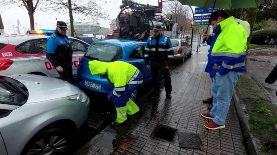 Los operarios municipales y la policía local de Gijón desatascan varios sumideros para evitar inundaciones en el centro