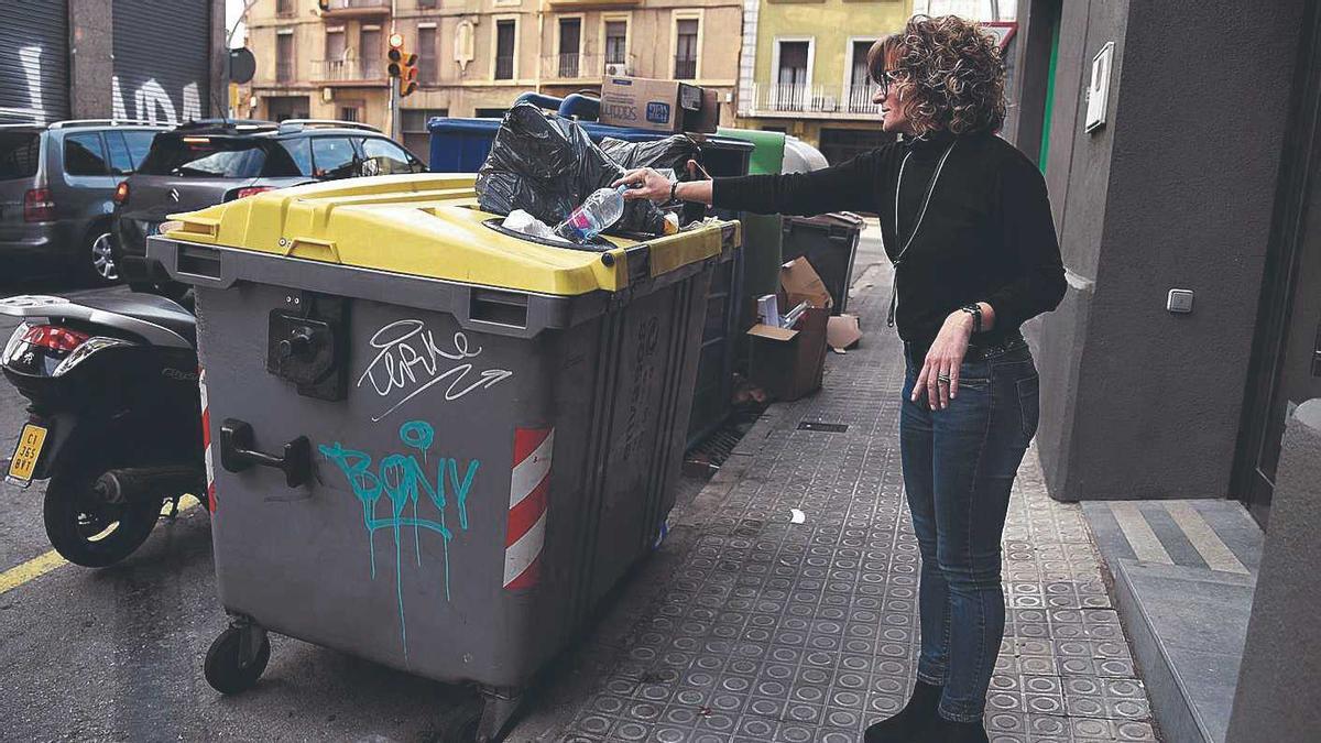 Una dona llançant un envàs en una zona de contenidors.