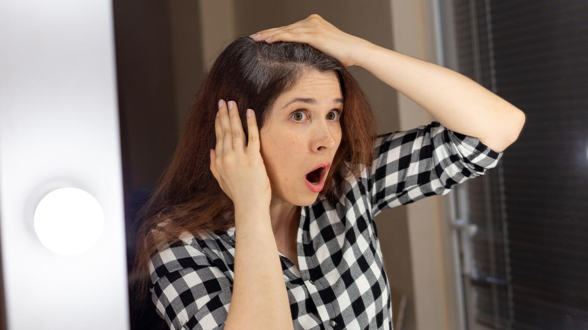 Una mujer observa su pelo canoso