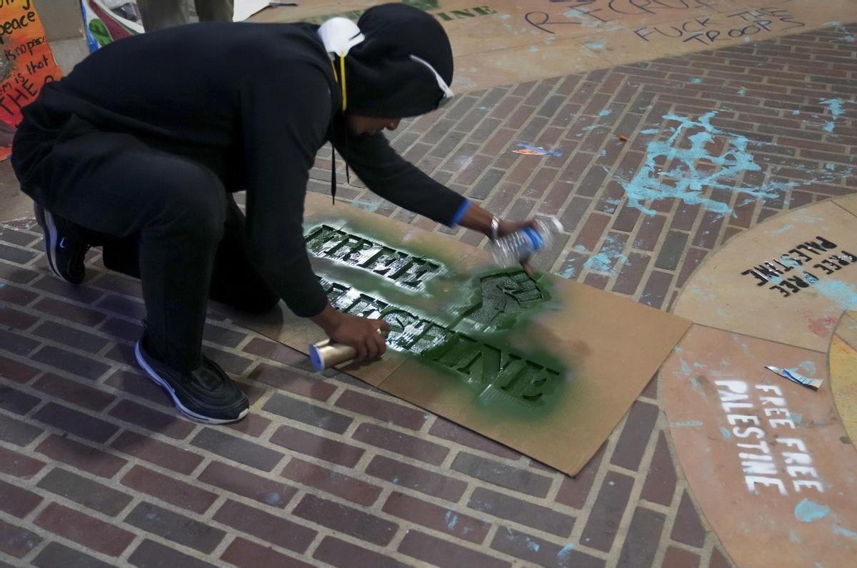 Los Angeles (United States), 02/05/2024.- A person spray paints signs inside the ongoing encampment of pro-Palestinian protestors on the campus of University of California Los Angeles (UCLA) in Los Angeles, California, USA, 01 May 2024. Nationwide protests have sprung up across the country on school campuses, many calling for institutions to divest investments in Israel and in support of a ceasefire in the Gaza conflict. (Protestas) EFE/EPA/ALLISON DINNER