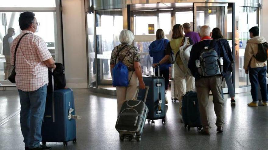 Varios pasajeros guardando cola para salir del Aeropuerto de Santiago-Rosalía de Castro tras aterrizar en el aeródromo/ Antonio hernández