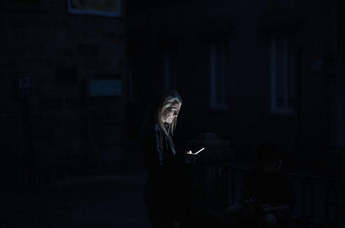 Una ourensana mira su móvil durante el apagón. | Brais Lorenzo / EFE