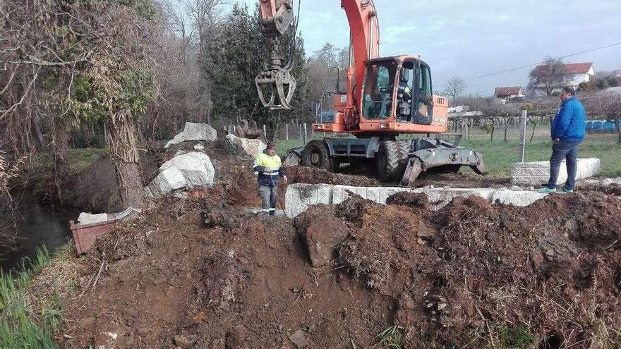 Unos operarios construyen uno de los muros de contención de piedra en el río Maceiras. // FdV