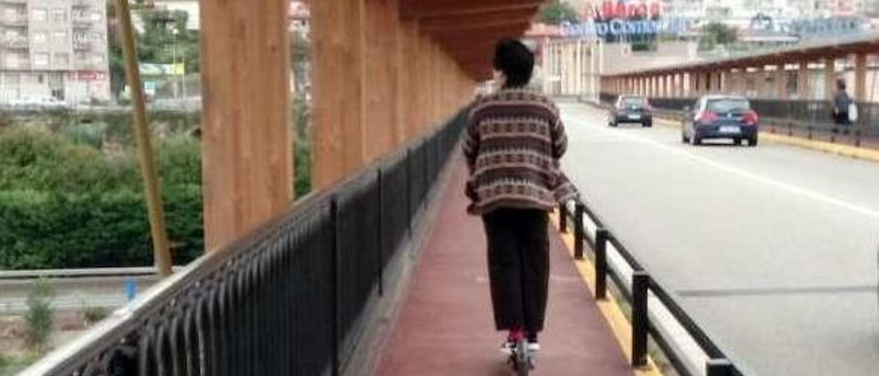 Una mujer pilota su patinete eléctrico por una de las aceras del puente de A Barca. // FdV