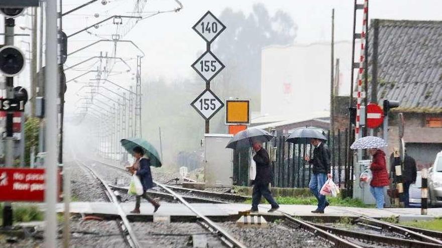 Unas personas cruzan el paso a nivel en Porriño, ayer. // A. H.