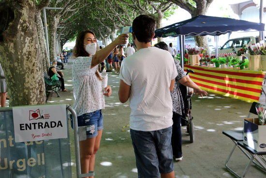 Una voluntària prenent la temperatura a una persona que vol accedir al recinte del passeig Joan Brudieu de la Seu d'Urgell