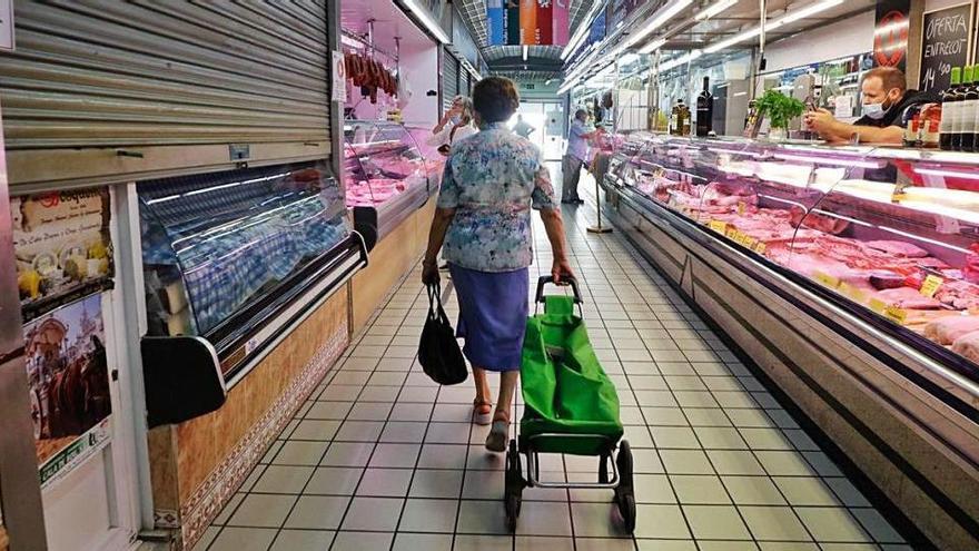 Una mujer, de espaldas, tira de su carro de la compra en el Mercat Nou de Vila.